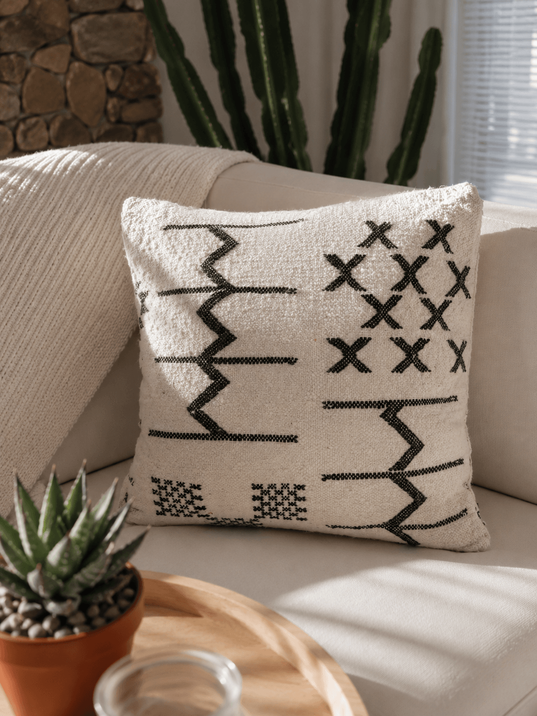 Housse de coussin berbère artisanale sur fond écru texturé